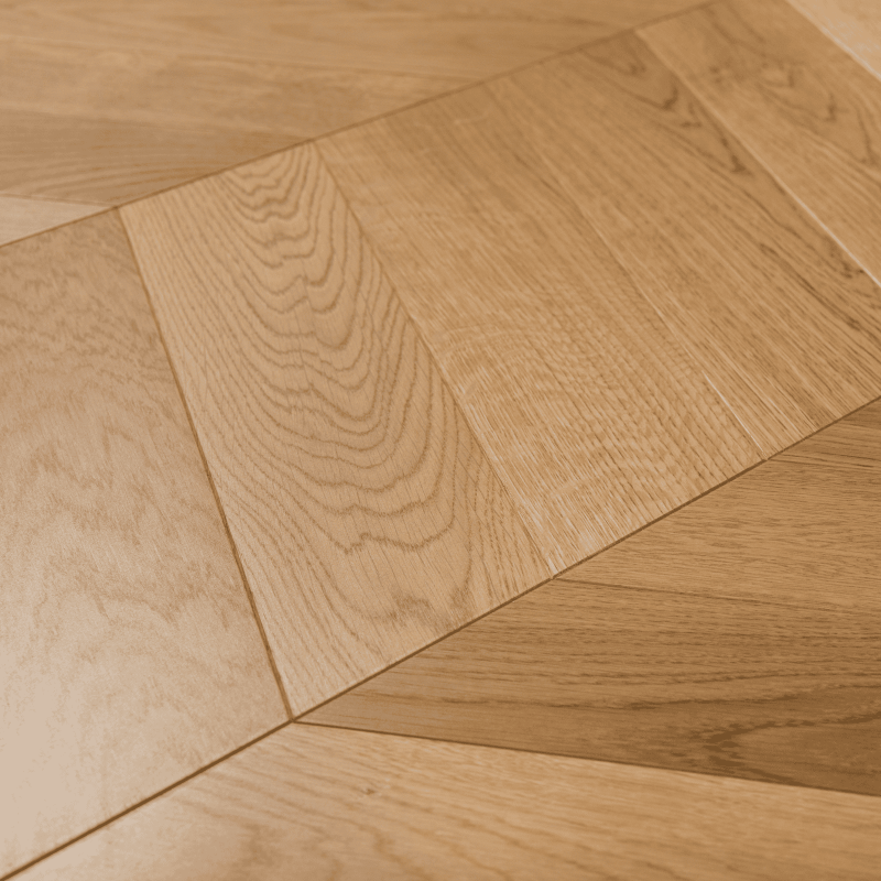 Suprafața parchetului stratificat în format chevron 60 lăcuit mat, bizotat pentru un living, dormitor, birou modern, clasic, cu stil.